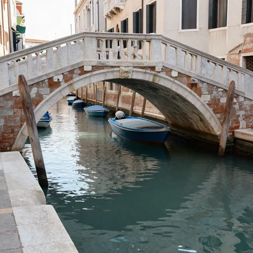 Canale laterale di Venezia con ponte di pietra, barche ormeggiate e persiane chiuse