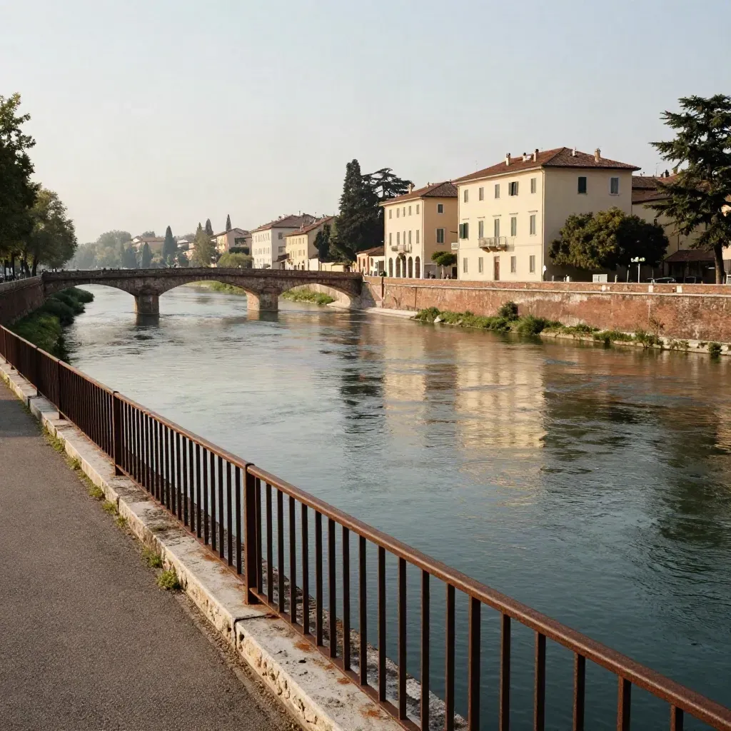 Curva del fiume a Verona con ponte basso, case chiare e rive alberate al tramonto.